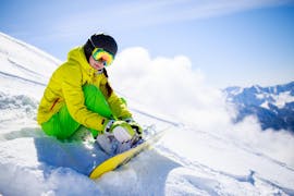 Ein Snowboarder checkt seine Bindung bei seiner Privaten Snowboardkurs für Kinder & Erwachsene aller Levels mit Active Snow Team Engelberg.