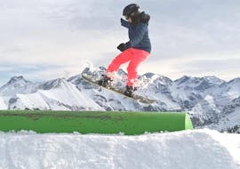 A child is enjoying the Private Snowboarding Lessons for Kids & Adults  - All Levels while trying some freestyle tricks under the supervision of an instructor from Alpin Skischule Oberstdorf.