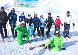 Een groep volwassenen met twee instructeurs van Alpin Skischule Oberstdorf genieten van hun pauze tijdens de skilessen voor volwassenen - gevorderd.