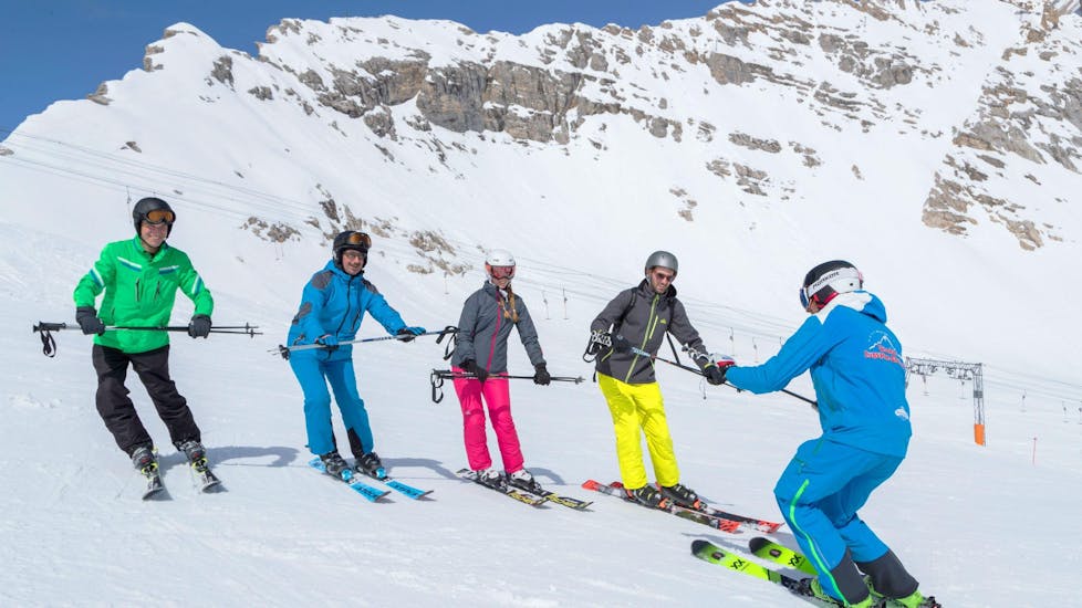 Een skileraar van de skischool Skischule Zugspitze-Grainau leert een groep skiërs de juiste skitechniek tijdens hun skilessen voor volwassenen - alle niveaus in het skigebied van Garmisch-Classic.