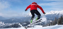 A snowboard instructor from the Sport Aktiv Seefeld ski school during a jump in the park.