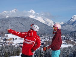 Un maestro di sci della scuola di sci Sport Aktiv Seefeld mostra ai suoi allievi una montagna in lontananza.
