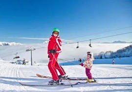 A little girl is having fun with her private ski instructor during private ski lessons for kids of all levels with Skischule Waidring Steinplatte.
