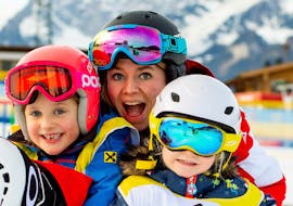 A instructor and her pupils during the Kids Ski Lessons "Mini-Yappy" (3-4 y.) for Beginners with the Snow Sports School Eichenhof St. Johann.