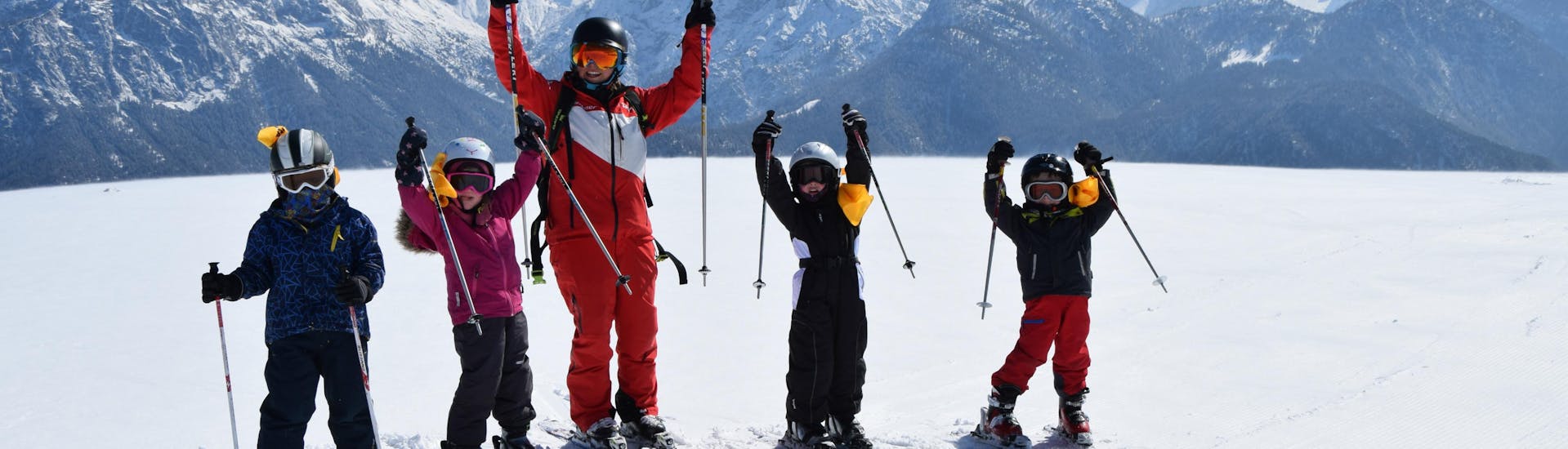 An instructor and its pupils waving at the camera during the Kids Ski Lessons (4-11 y.) for Beginners.