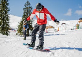 Un homme essayant la prise de carre pendant Cours de snowboard pour (dès 8 ans) pour Expérimentés avec l'école de ski HERBST Ski School Lofer.