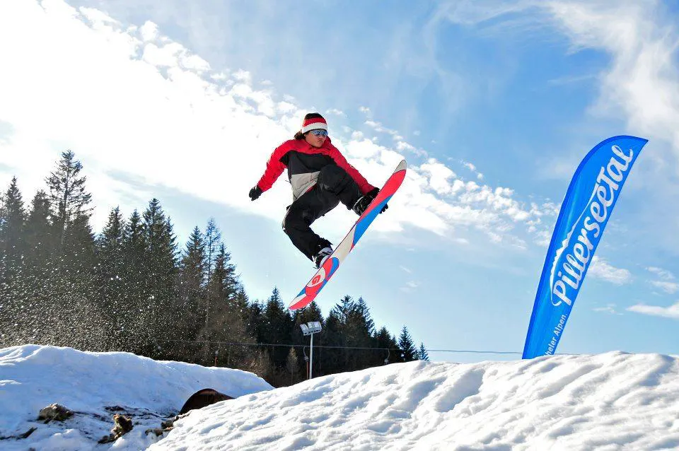 Snowboardlessen voor kinderen en volwassenen (vanaf 11 jaar) voor gevorderde snowboarders met Skischule Waidring Steinplatte Een snowboarder springt in het funpark tijdens snowboardlessen voor kinderen en volwassenen voor gevorderden met Skischule Waidring Steinplatte.