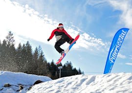 Uno snowboarder salta nel fun park durante le lezioni di snowboard per bambini e adulti per esperti della Skischule Waidring Steinplatte.