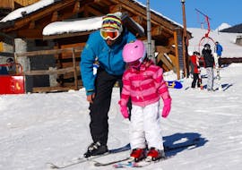 A young skier is learning how to ski with the support of her ski instructor from the ski school Snocool in Tignes during her Private Ski Lessons for Kids - All Ages.