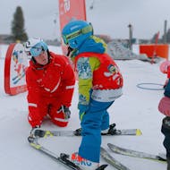 Een kleine skiër met haar skileraar tijdens de kinderskilessen voor beginners bij de skischool Kreischberg - Mayer.