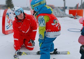 Een kleine skiër met haar skileraar tijdens de kinderskilessen voor beginners bij de skischool Kreischberg - Mayer.