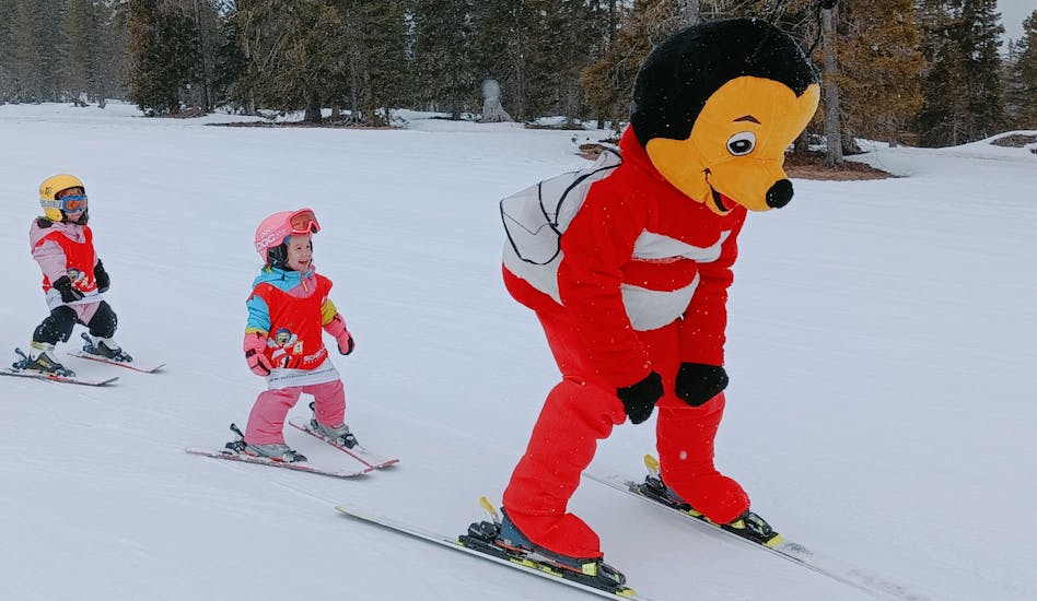 Kinder fahren mit dem Maskottchen "Biene 'Mayer" beim Kinder-Skikurs (4-12 J.) für Anfänger.
