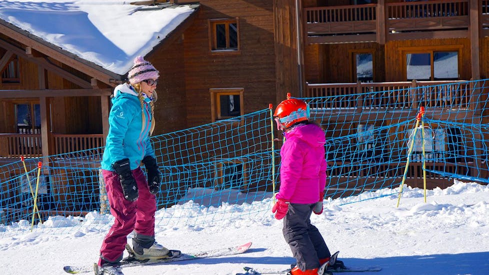 A child takes the first steps on skis during the Private Ski Lessons for Kids - All Ages and is guided by an experienced instructor from the ski school Snocool.