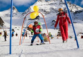 Ein Kind hat Spaß beim Kinder-Skikurs “Schneeflöhe” (3-5 J.) für Anfänger mit Schweizer Skischule Saas-Grund.