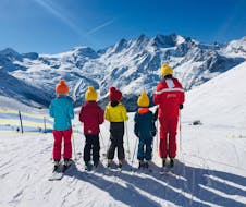 Vier Kinder und eine Skilehrerin stehen in der Reihe auf der Piste beim Kinder-Skikurs (6-12 J.) für alle Levels mit Schweizer Skischule Saas-Grund.