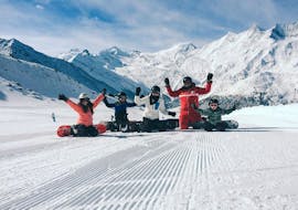 Vier Kinder und ein Snowboardlehrer jubeln beim Snowboardkurs für Kinder (6-12 J.) für Anfänger mit Schweizer Skischule Saas-Grund.