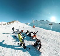Snowboarders are sitting in the snow before their Adult Snowboarding Lessons for All Levels with Prosneige Val Thorens & Les Menuires.