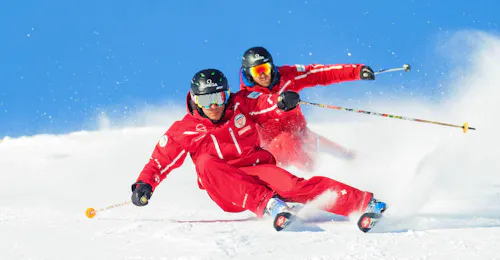 Cours particulier de ski pour Adultes avec École Suisse de Ski de Crans-Montana Deux moniteurs de l'école suisse de ski de Crans-Montana font une démonstration de carving pendant un cours particulier de ski pour adultes.