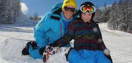 Ein Lehrer der ESI Generation und ein Kind genießen eine Snowboardkursstunde für Kinder und Jugendliche in Serre-Chevalier.