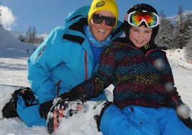 An instructor of ESI generation and a kid are enjoying a snowboarding lesson for kids and teens in Serre-Chevalier.