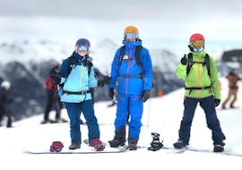 Twee volwassenen en een instructeur van de ESI-generatie zijn klaar om hun snowboardles voor volwassenen in Serre-Chevalier te beginnen.