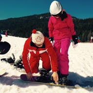 Snowboard instructor helping setting up during a Private Snowboarding Lessons (6-14 y) for Kids of all Levels with Skischule Mösern - Seefeld.