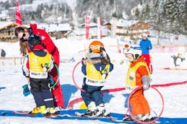 Drie kinderen spelen tijdens de skilessen voor kinderen "bambini" (3-4 j.) bij skischool Jochberg in Jochberg.