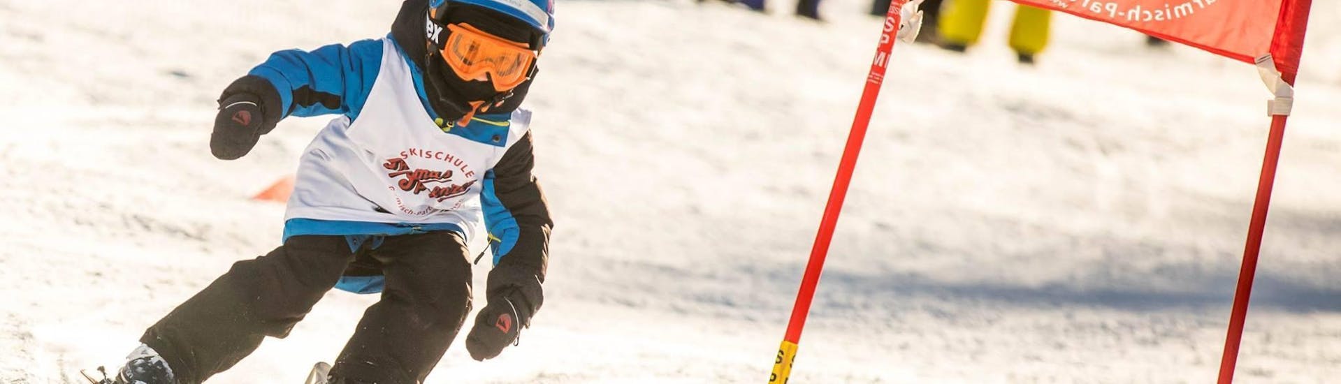 Een jong kind racet over een racebaan als onderdeel van de kinderskilessen (4-12 jaar) - alle niveaus bij de skischool Skischule Thomas Sprenzel in het skigebied Garmisch-Classic.