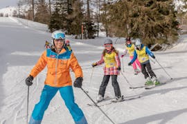 A group of children is skiing in line during their teen ski lessons for first-timers with skischule Thommi at Nassfeld.