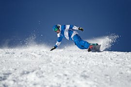 Un snowboarder montre sa technique de carving dans le scénario de la montagne blanche pendant les cours de snowboard pour enfants et adultes - tous niveaux avec l'école de ski Skischule Thomas Spenzel.