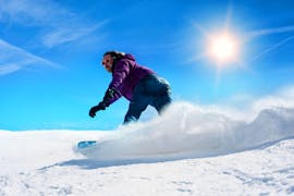 Snowboarder takes a tight turn on a sunny day during his Private Snowboarding Lessons for Kids & Adults - All Levels with the ski school Skischule Thomas.
