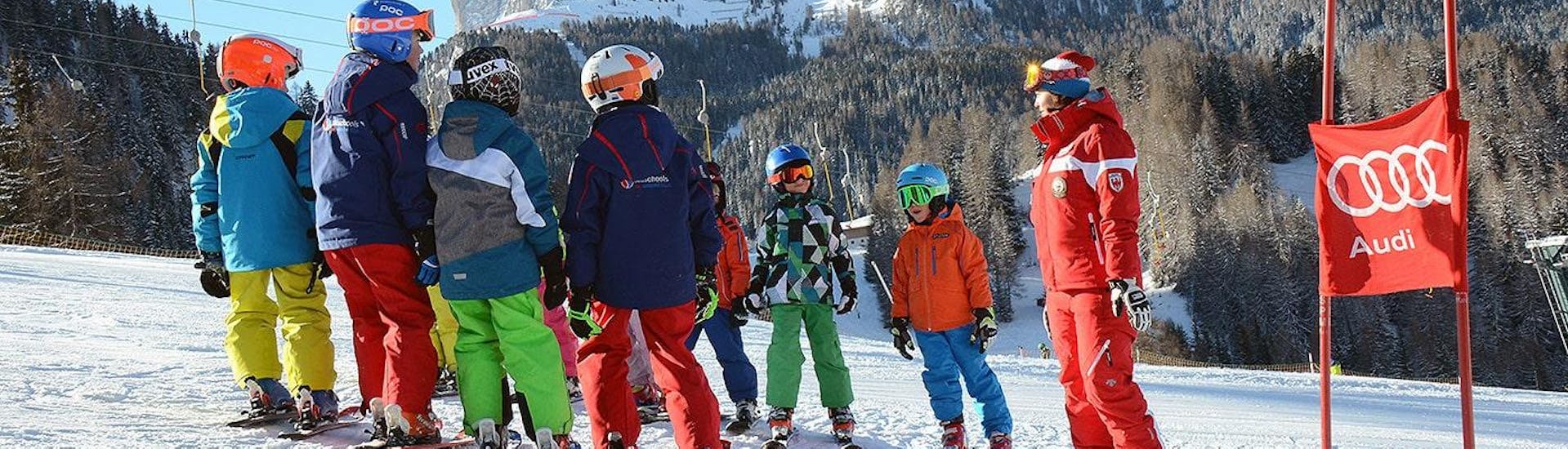 Maestro di sci che dà ai giovani partecipanti gli ultimi consigli prima della gara. Queste lezioni di sci per bambini per sciatori esperti sono ideali a Selva di Val Gardena.