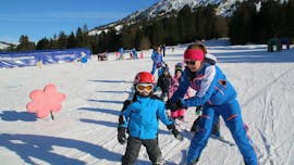 Een instructeur en een kind naast elkaar tijdens de Kids Skilessen (3-12 j.) voor alle niveaus.