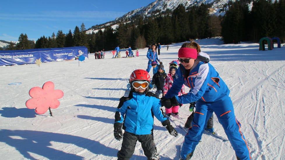 Un moniteur et un enfant se tenant l'un à côté de l'autre lors des cours de ski pour enfants (3-12 ans) pour tous les niveaux.