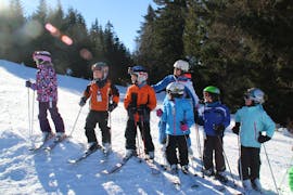 Niños y un instructor de esquí en fila en la pista en las Clases de esquí para niños (3-12 años) + Paquete de alquiler de esquís de la Escuela de esquí y snowboard Ostrachtal.