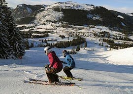 Deux adultes skiant lors des cours de ski pour adultes de tous niveaux de l'école de ski et de snowboard Ostrachtal.
