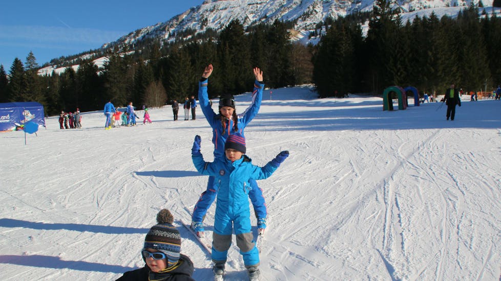 Ein Kind und ein Skilehrer jubeln beim Privat-Skikurs für Kinder aller Altersstufen der Ski- & Snowboardschule Ostrachtal.