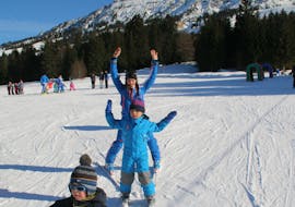 Een kind en een skileraar juichen tijdens privélessen skiën voor kinderen van alle leeftijden van Ski & Snowboardschool Ostrachtal.