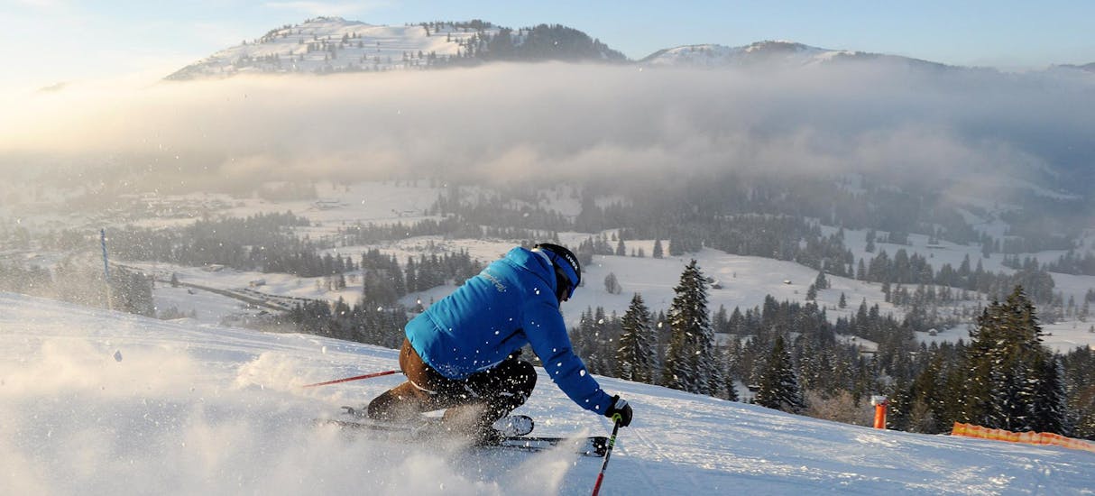 Un adulte dévalant une piste de ski lors des leçons de ski privées pour adultes de tous niveaux de l'école de ski et de snowboard Ostrachtal.