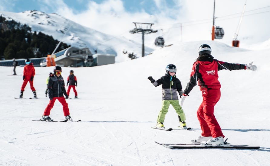 Ein Skilehrer zeigt Kindern den Weg im Kinder-Skikurs (4-16 J.) für Fortgeschrittene.