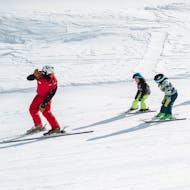 Der Skilehrer winkt den Kindern hinter ihm im Kinder-Skikurs (4-16 J.) für Anfänger mit Skischule Obergurgl.