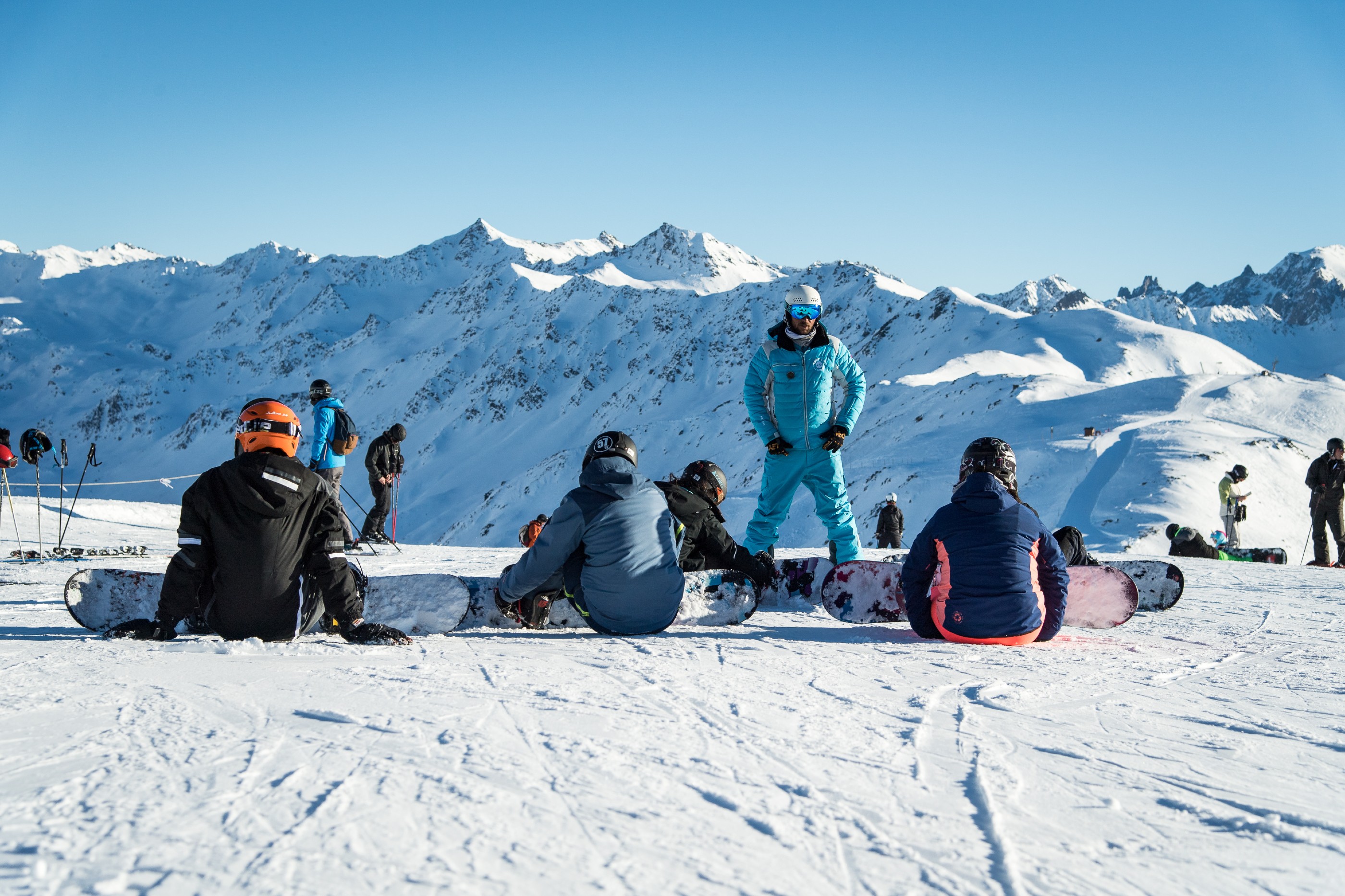An ESI Ozone instructor explains to his students during a private snowboarding lesson the fundamental techniques of snowboarding on the slopes of Les Orres.