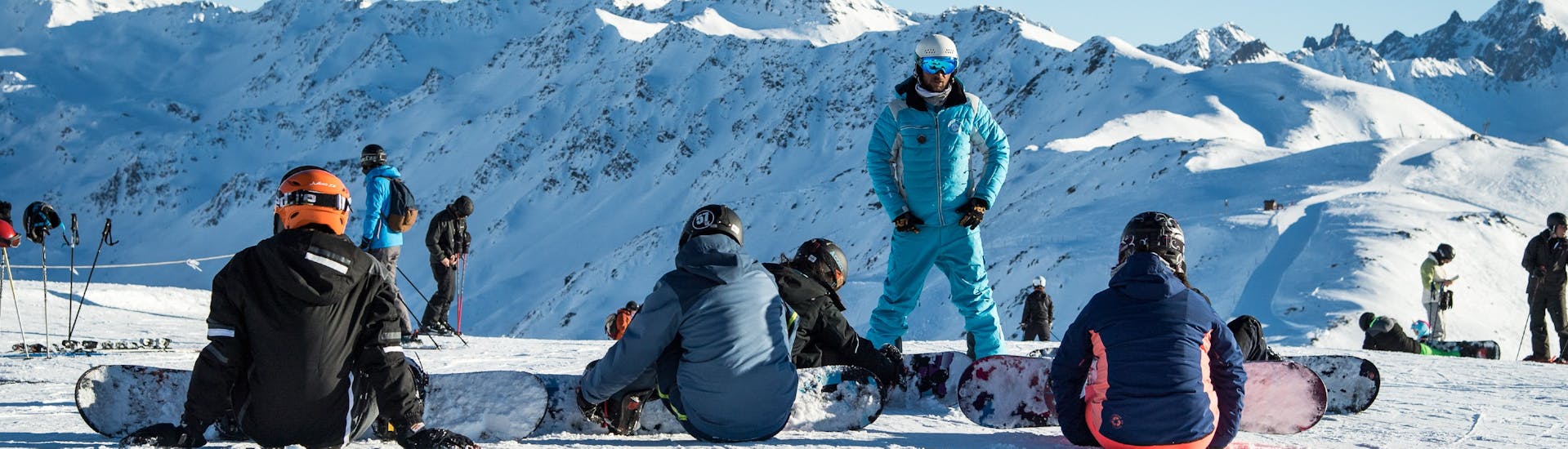 An ESI Ozone instructor explains to his students during a private snowboarding lesson the fundamental techniques of snowboarding on the slopes of Les Orres.