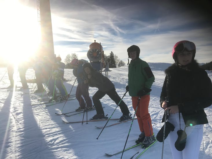 Jugendliche und ein Skilehrer stehen in einer Reihe auf der Piste beim Teenager-Skikurs (13-18 J.) für alle Stufen der Ski- & Snowboardschule Ostrachtal.