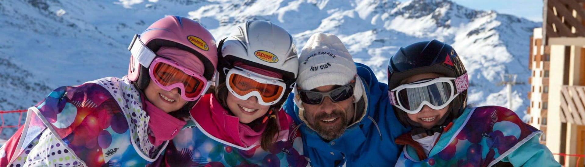 A group of children in full skiing gear are smiling at the camera together with their ski instructor from the ski school Prosneige Val Thorens & Les Menuires while preparing for their Private Ski Lessons for Kids - All Ages - High Season.