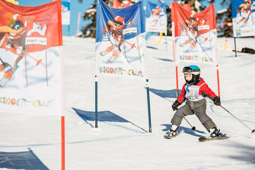 Een kleine skiër daalt in het Kinderland tijdens de kinderskilessen "BOBO's Kids-Club" voor beginners met de Busslehner Achkirch Skischool de piste af.