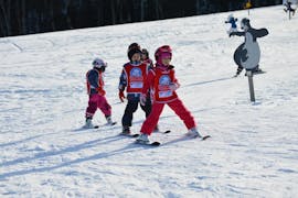 Een groep kinderen oefent op de piste tijdens privé-skilessen voor kinderen van alle niveaus bij de Schi- & Snowboardschule.