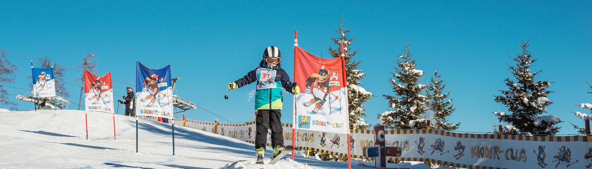 Een leerling skiet op een blauwe piste tussen de poorten tijdens zijn kinderskilessen "BOBO's Kids-Club" voor gevorderden bij de Busslehner Achenkirch Skischool.