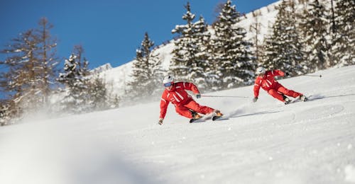 Lezioni private di sci per adulti per tutti i livelli con Skischule Busslehner Achenkirch Due maestri di sci della scuola di sci Busslehner Achenkirch scendono insieme su una pista.