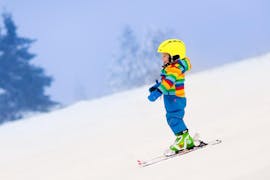 A small boy is gliding down a slope during his private ski lessons for kids of all ages in Stubai with Skischule Stubai Tirol.